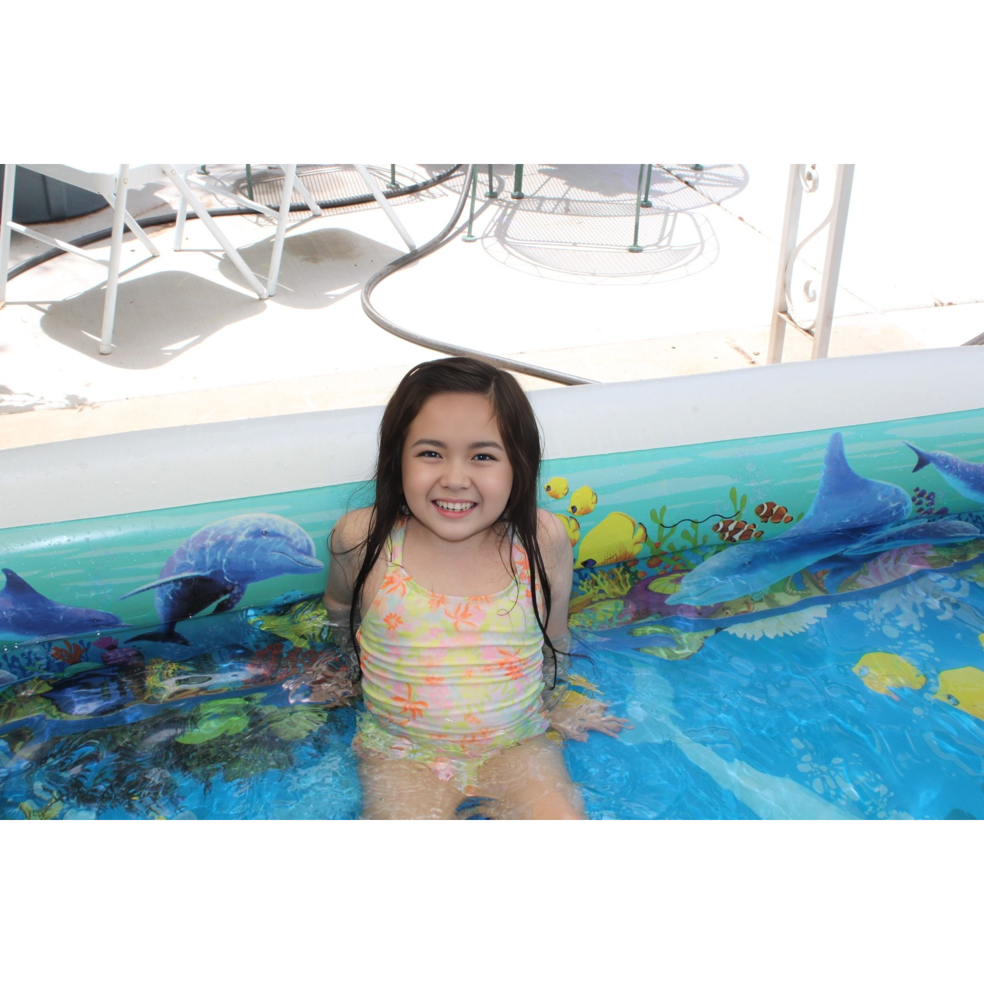 a little girl sitting in a swimming pool